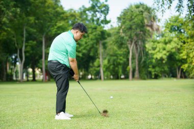 Mutlu Asyalı erkek amatör golfçü sabah golf sahasında golf oynamaktan zevk alır. Asyalı şişman adam golf oynamaya gidiyor..