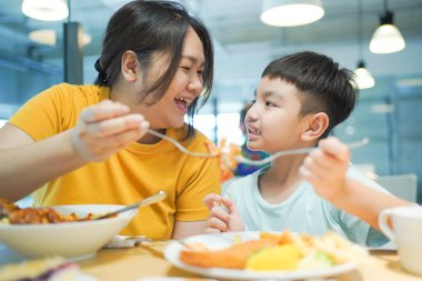 Mutlu Asyalı bekar anne ya da çocuk yaşam tarzı olan bekar anne ailesi. Anne ve oğlu balık ve patates lokantasında birlikte öğle yemeği yiyorlar. Annem restoranda balık ve cips yiyor..
