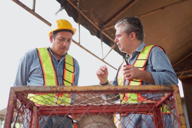 Mühendisler inşaat alanında aktif olarak çalışıyorlar, birbirleriyle detaylı tartışmalara giriyorlar. İnşaat projesinin çeşitli yönlerini işbirliği içinde inceliyorlar..