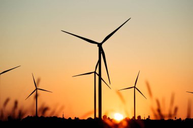 Elektrik jeneratörü yel değirmenlerinin manzara fotoğrafçılığı kırsal bölgedeki güzel günbatımı gökyüzüne yerleştirildi. Sürdürülebilir ve temiz enerji kavramı.