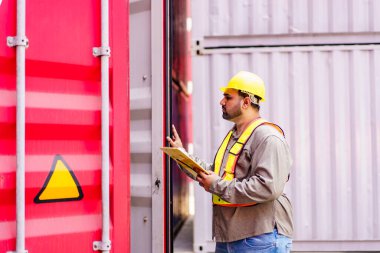 Asian male logistic worker in safety workwear portrait at the container yard. Logistic foreman portrait. Male logistic supervisor is inspecting the incoming cargo container at container yard.
