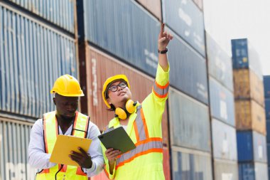 Erkek gümrük memurları şu anda konteyner alanındaki konteynırları inceliyor. Memur ayrıca gelen ve giden kargo sayımını da yapıyor..