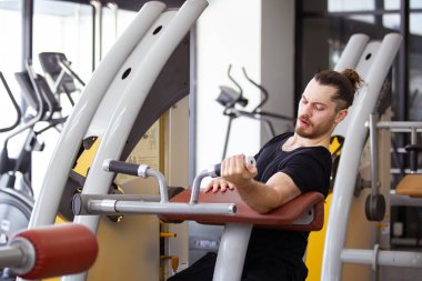 Good looking and muscular hispanic man doing a weight training exercise in the gym, a man focus a weight training at the arm and upper body. Healthy lifestyle concept.
