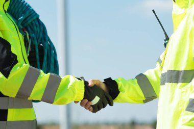 Team of professional electrical engineers in fully safety suit are working and discussing together at the windmill electric generating turbine. Electricians working at the site of windmill turbine.