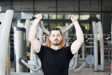 Good looking and muscular hispanic man doing a weight training exercise in the gym, a man focus a weight training at the arm and upper body. Healthy lifestyle concept.
