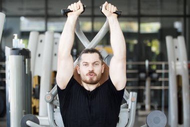 Good looking and muscular hispanic man doing a weight training exercise in the gym, a man focus a weight training at the arm and upper body. Healthy lifestyle concept.