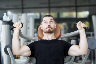 Good looking and muscular hispanic man doing a weight training exercise in the gym, a man focus a weight training at the arm and upper body. Healthy lifestyle concept.