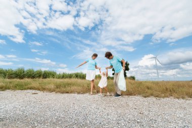 Kızı olan mutlu beyaz beyaz bir aile, arka planda yel değirmeni kuleleriyle gündüz vakti birlikte yürüyor ve dinleniyorlar. Mutlu aile aktivitesi konsepti.