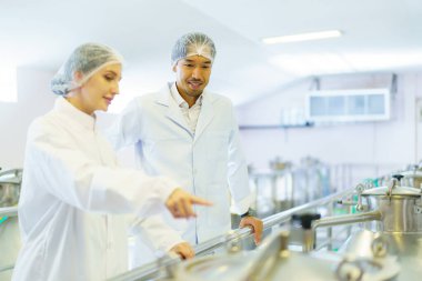 Kalite kontrol memurları ya da fabrika mühendisleri içecek üretim tesisinin içini inceliyor. Gıda üretim fabrikasında çalışan kadın ve erkek mühendisler..