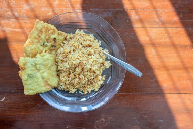 Masanın üzerinde iki kızarmış tempeh ile kızarmış pirinç menüsü olan bir kahvaltı tabağının fotoğrafı.