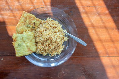 Masanın üzerinde iki kızarmış tempeh ile kızarmış pirinç menüsü olan bir kahvaltı tabağının fotoğrafı.