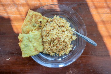 Masanın üzerinde iki kızarmış tempeh ile kızarmış pirinç menüsü olan bir kahvaltı tabağının fotoğrafı.