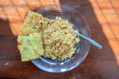 Masanın üzerinde iki kızarmış tempeh ile kızarmış pirinç menüsü olan bir kahvaltı tabağının fotoğrafı.