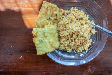 Masanın üzerinde iki kızarmış tempeh ile kızarmış pirinç menüsü olan bir kahvaltı tabağının fotoğrafı.