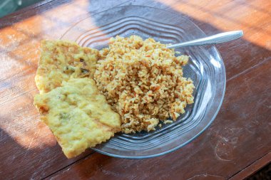 Masanın üzerinde iki kızarmış tempeh ile kızarmış pirinç menüsü olan bir kahvaltı tabağının fotoğrafı.