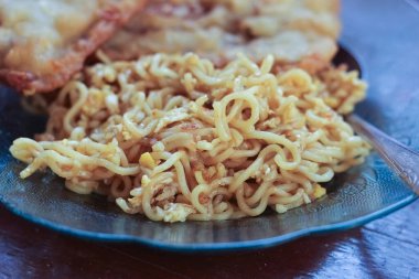 Kahvaltı tabağının fotoğrafı masanın üstünde 2 kızarmış tempeh 'li kızarmış erişte menüsü ve cam bir tabakta servis ediliyor.