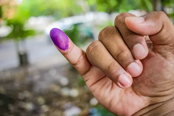 a picture of a man's hand. The ink on a man's finger was obtained after voting during the regional elections (pilkada) in Semarang, Indonesia