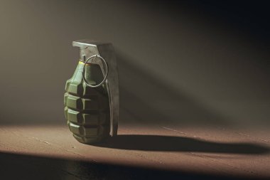 Karanlık, ahşap bir zeminde, ışıkla aydınlatılmış bir el bombası. Tehlike, savaş, yıkım kavramı. Karanlık arka plan ve el bombasına odaklanmak gerginlik yaratıyor. 3d hazırlayıcı
