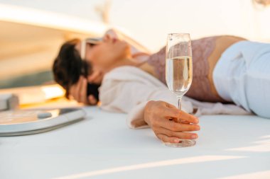 Mutlu Kafkasyalı kadın gün batımında okyanusta yelken açan yolcu gemisinde rahatlıyor ve şampanya içiyor..