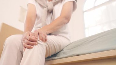 Dizi ağrıyan yaşlı kadın yatakta oturuyor.