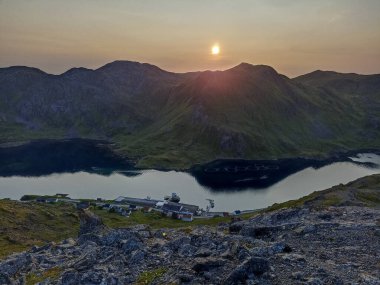 The view of the sunset over Kamoyvaer village, Rishfjorden, and Rishamntind Mountain on Mageroya Island, Finnmark, Norway clipart