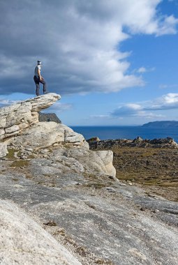 Mageroya Adası, Finnmark, Norveç 'teki Minitrolltunga' dan Duksfjorden manzarasının tadını çıkaran bir kadın yürüyüşçü.