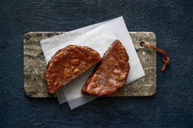 Parşömen kağıdıyla mermer bir tahtanın üzerindeki iki browni yarısının yukarıdan görünüşü. Çatlak kabuk ve yoğun, sarkık doku. Koyu arkaplanı olan kırsal bir sunum. Pastane menüleri, tatlı..