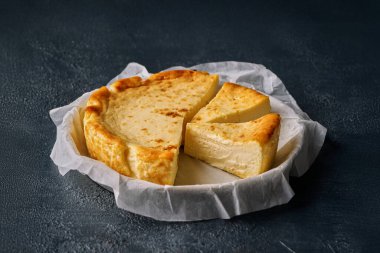 Parşömen kağıdına basklı cheesecake, kremalı şekersiz tatlı. Koyu mavi arka plan, seçici odaklanma. Pastane ya da restoran menüsü için ev yapımı tatlı. fırın kavramı.