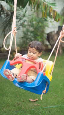 Küçük çocuk salıncakta bir iple oynuyor