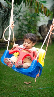 little boy playing with a swing in the park