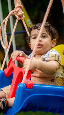 Küçük çocuk oyun sahasında ip ile oynuyor.