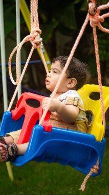 little boy playing with a swing in the park
