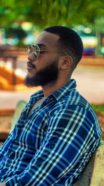 Parkta oturan adam kayıp bir bakışla düşünüyor.