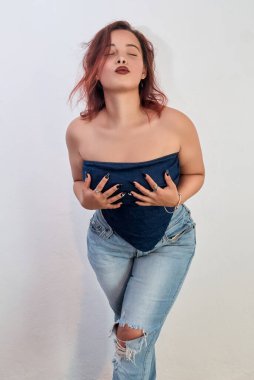 Beyaz arka planda poz veren güzel esmer bir kadının stüdyo çekimi.