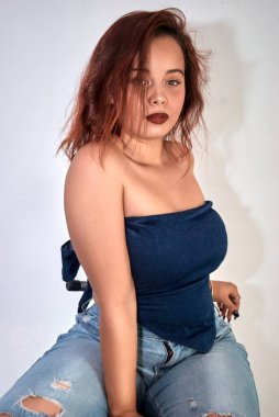 Kırmızı dudaklı ve beyaz arkaplanı olan genç bir kadının stüdyo portresi..