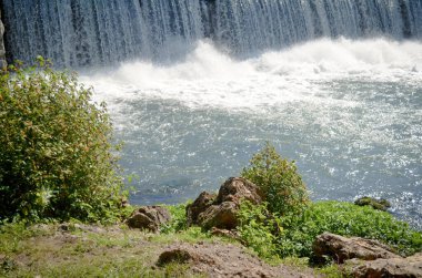 Nehir kıyısında, şelalenin dibinde. 