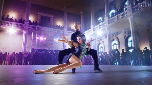 Couple dancers perform latin dance on large professional stage.