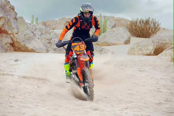 Young man practice riding dirt motorcycle. Splashing sand