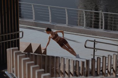 Genç bir kadın şehrin ortasında dışarıda egzersiz yapıyor.