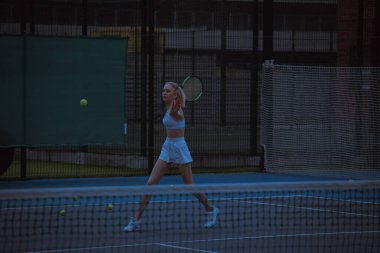 Kadın tenisçi tenis kortunda antrenman yapıyor.