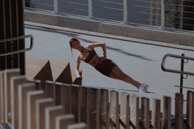 Genç bir kadın şehrin ortasında dışarıda egzersiz yapıyor.