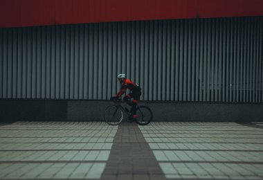 Şehirde bisiklete binen genç adam, gündüz manzaralı. 