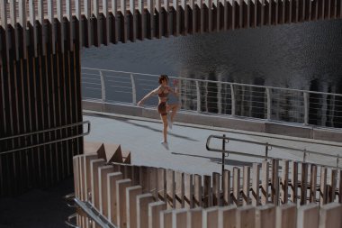 Genç bir kadın şehrin ortasında dışarıda egzersiz yapıyor.