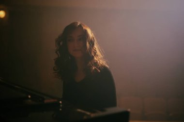 Konser salonunda piyano çalan kadın.