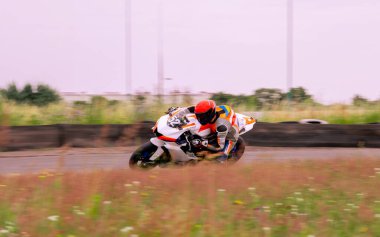 Bir motosiklet yarışçısı motosiklet pistinde hızlı sürüyor..