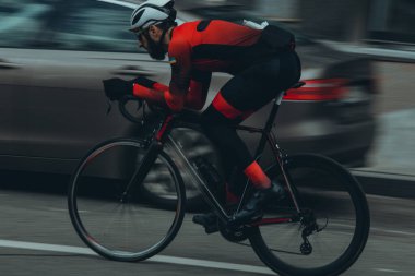 Şehirde bisiklete binen genç adam, gündüz manzaralı. 