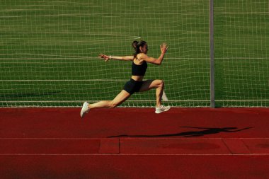 Atlet kız koşu pistinde antrenman yapıyor.