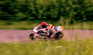 Bir motosiklet yarışçısı motosiklet pistinde hızlı sürüyor..