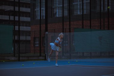 Kadın tenisçi tenis kortunda antrenman yapıyor.