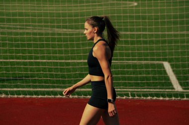 Atlet kız koşu pistinde antrenman yapıyor.